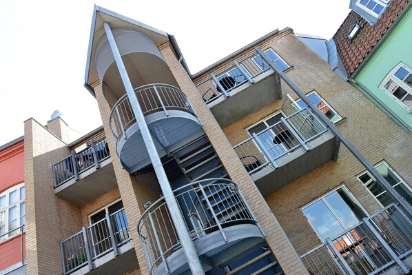 A multi-story residential building with balconies, brick facades, and multiple windows.
