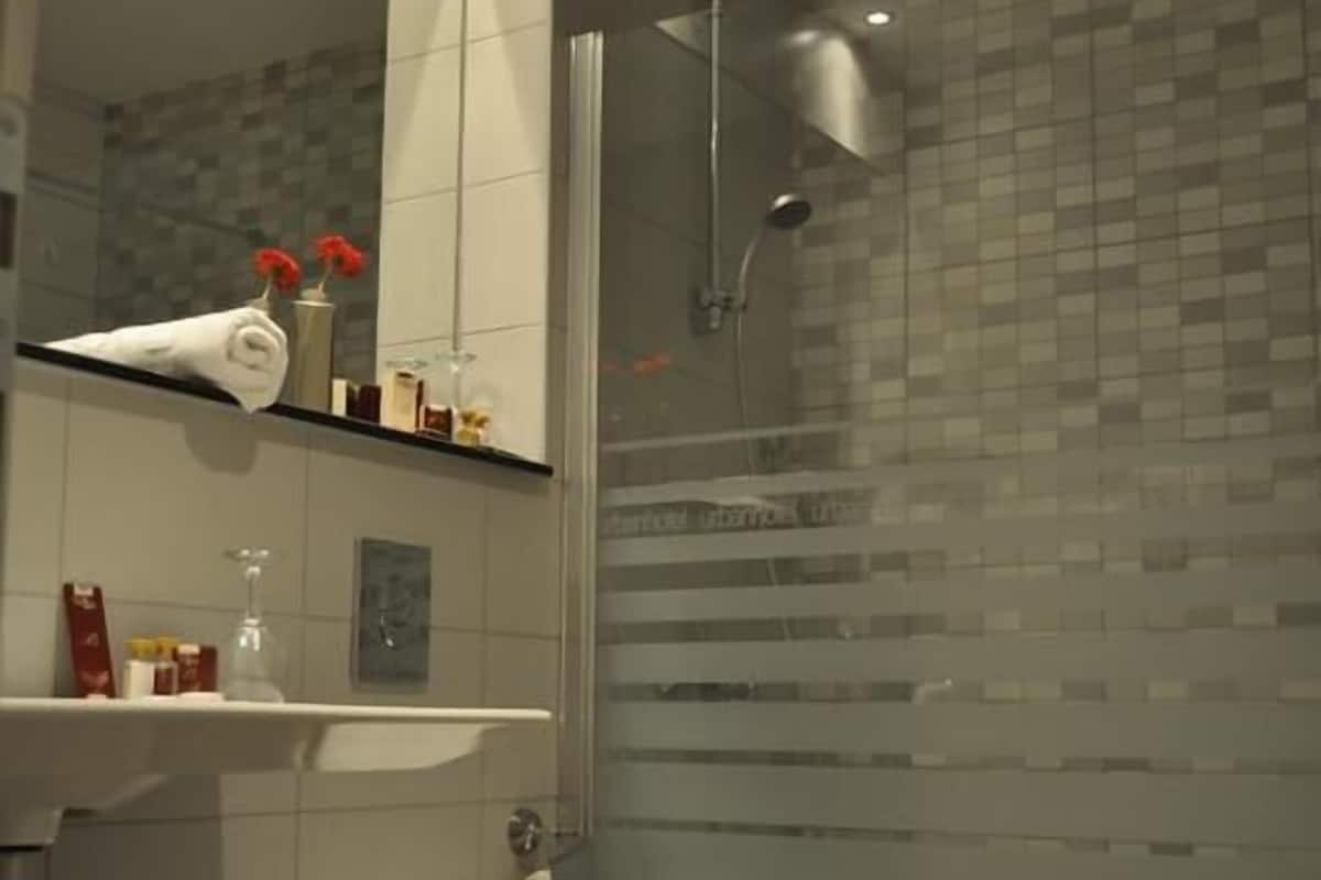 Un baño moderno con inodoro, ducha y tocador con espejo y estantes.