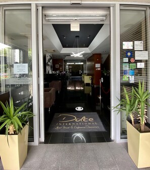 Entrada de l'Hotel Dolce International, amb taulell de recepció, zona de seients i una vista clara de l'interior.