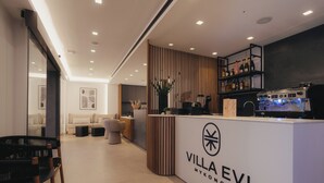 A modern hotel lobby with a reception desk, seating area, and a bar. - Evi Suites & Villas (Mykonos)