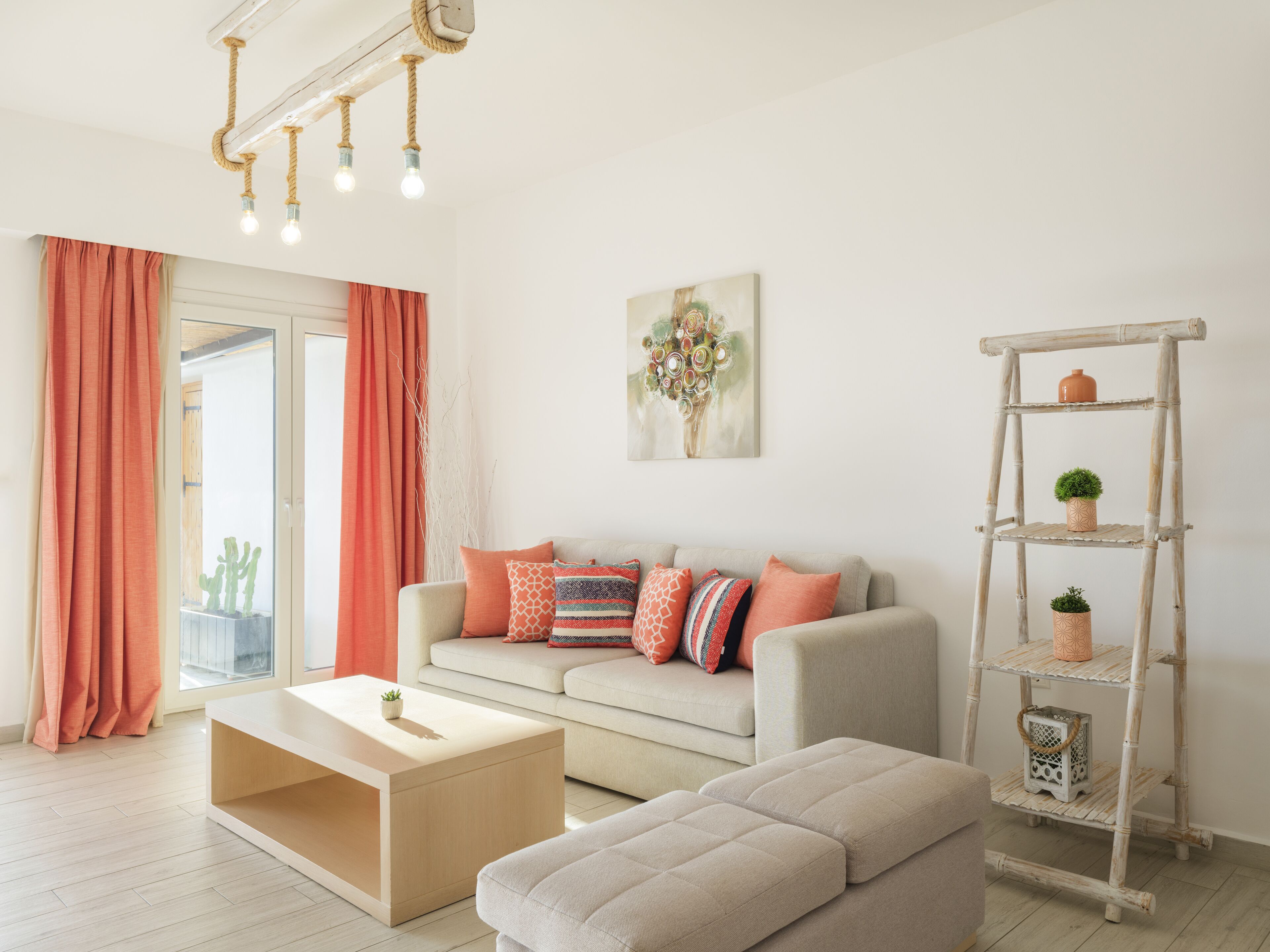 A living room with a sofa, ottoman, coffee table, and a decorative ladder shelf.