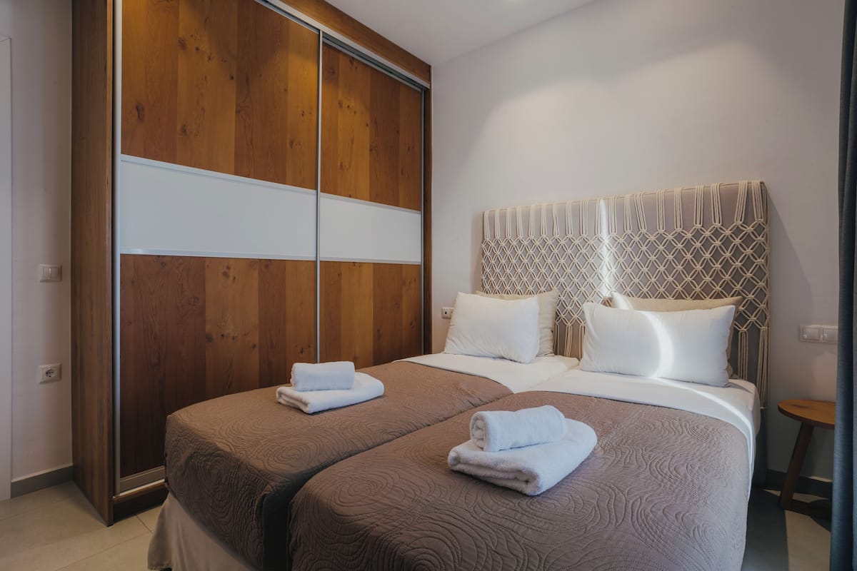 A hotel room with two beds, a wooden wardrobe, and a small round table.
