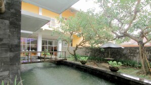 A courtyard with a small water feature, potted plants, and a stone wall. - University Hotel Yogyakarta (Yogyakarta)
