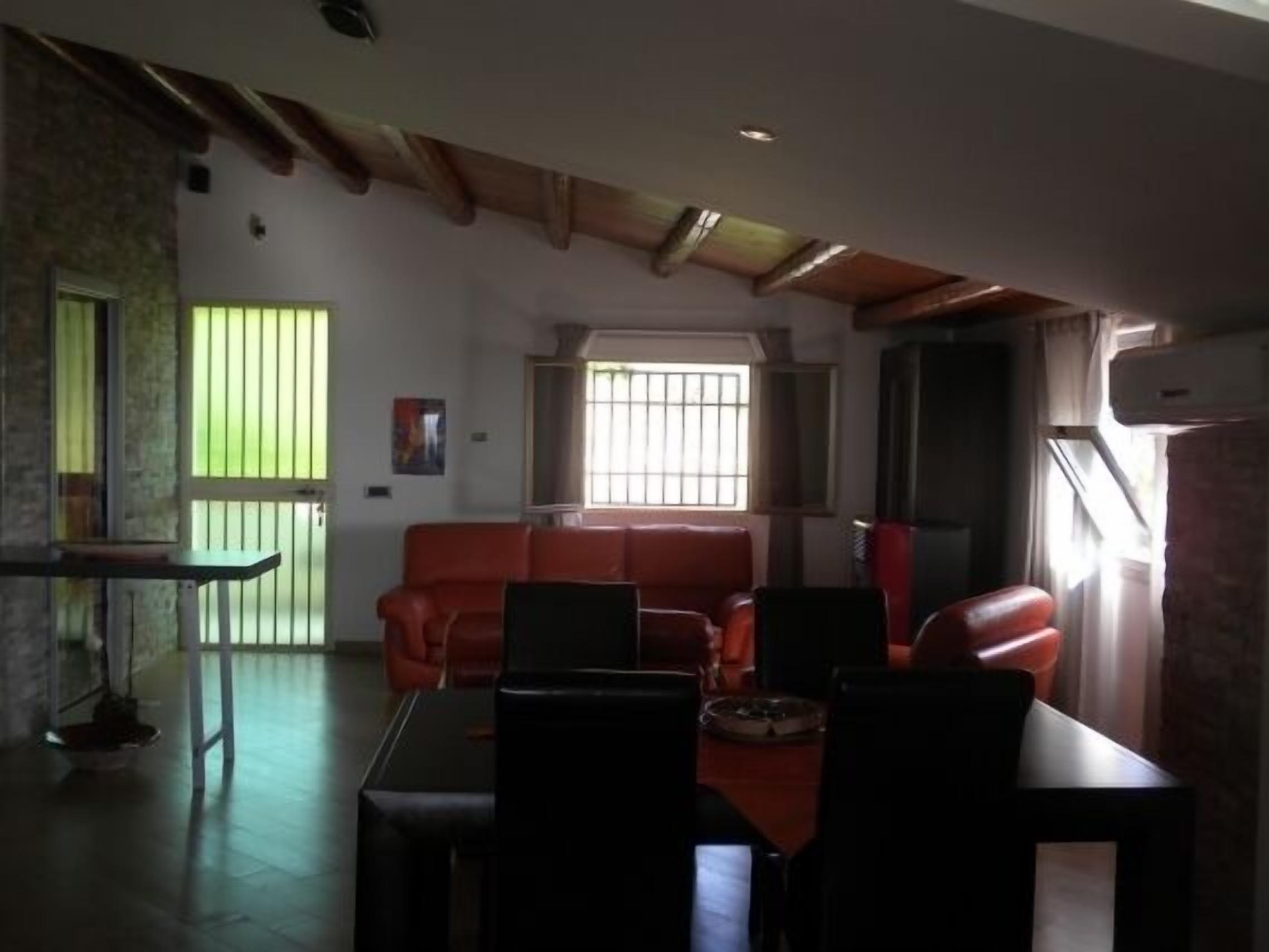 Una sala de estar con un sofá rojo, una mesa de comedor con sillas y un televisor.