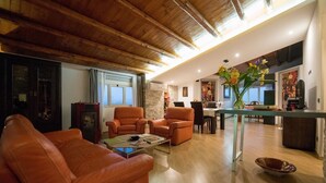 A spacious living room with leather sofas, a coffee table, and a dining area with a kitchen in the background. - Camagna Country House (Partanna)