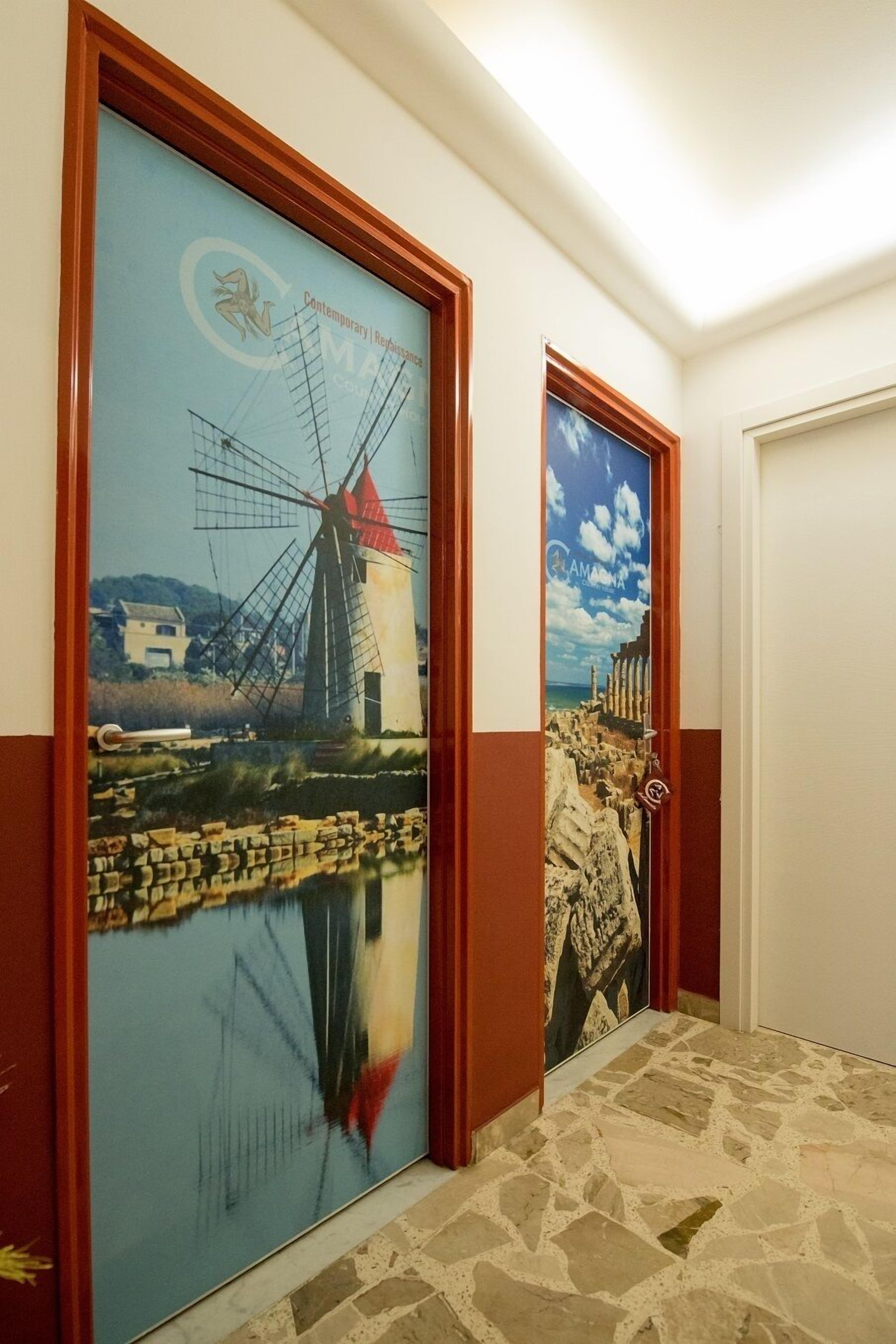 A hallway with two doors, each featuring a large mural of a windmill and a body of water.