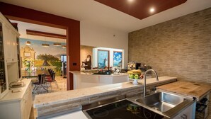 A modern kitchen with a central island, a built-in oven, and a stainless steel sink. - Camagna Country House (Partanna)
