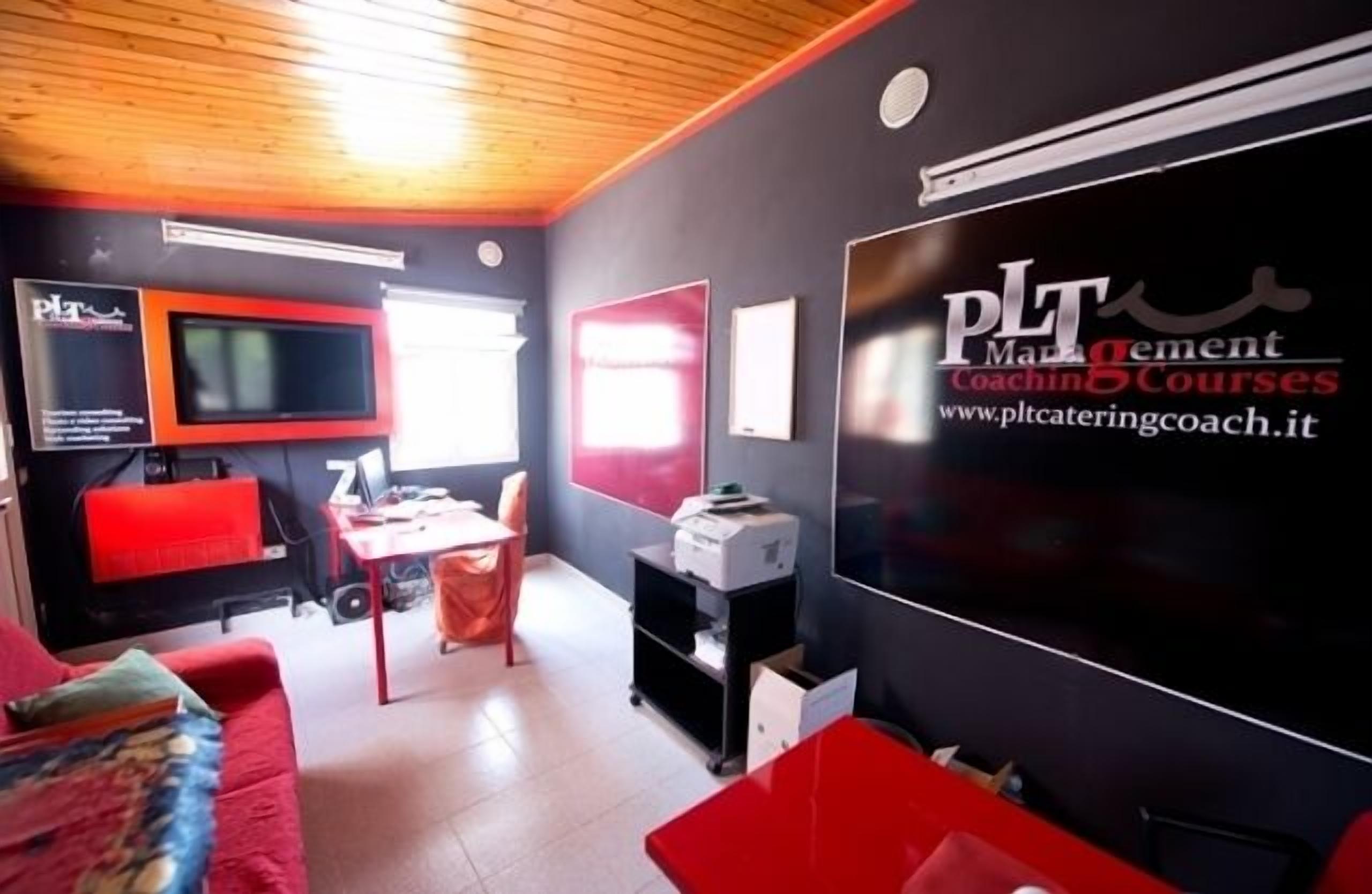 Ein modernes Zimmer mit einem Flachbildfernseher, einem roten Sofa, einem kleinen Tisch und einem Drucker.