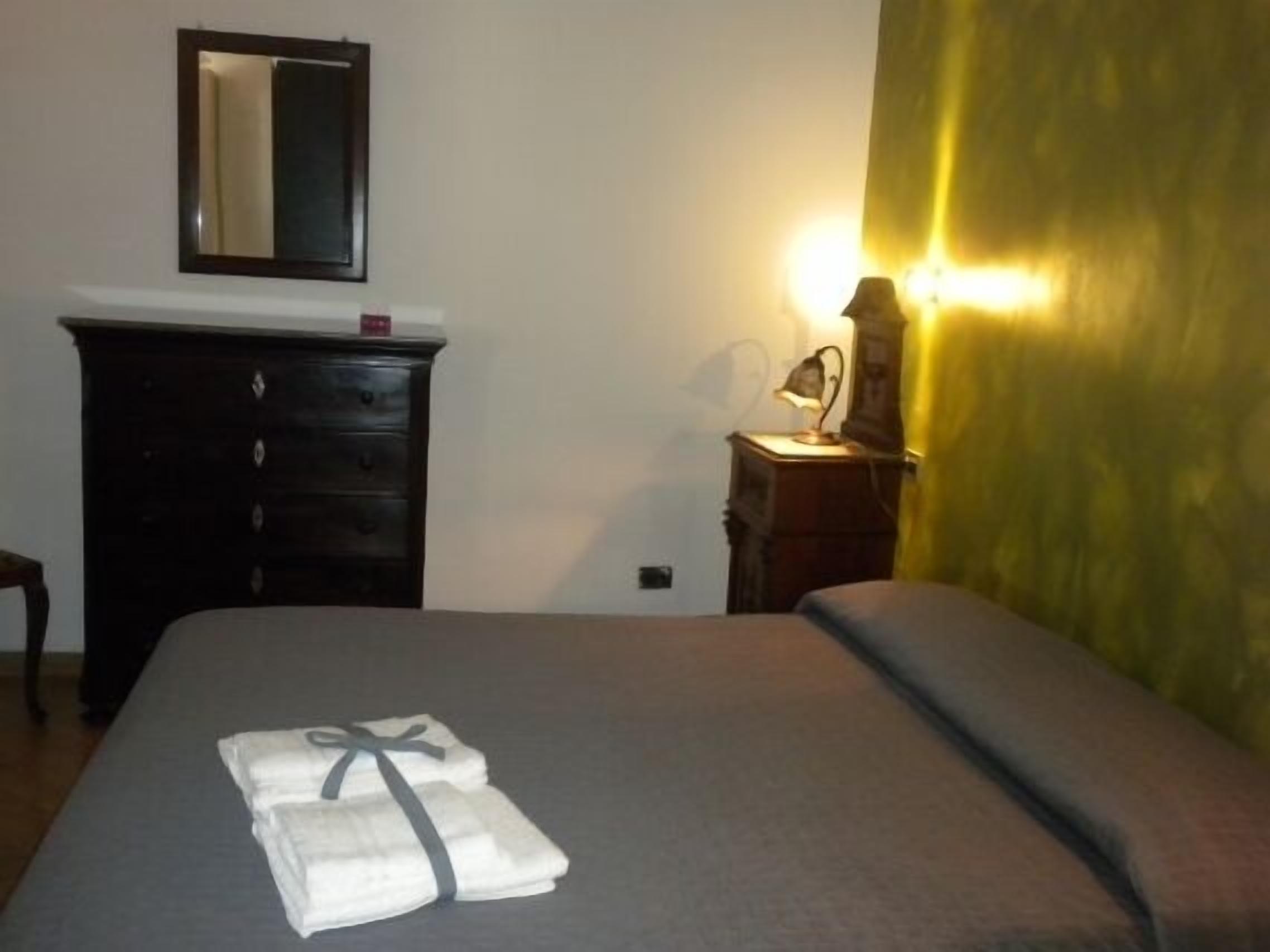 Une chambre d’hôtel avec un lit, une commode, un miroir et une lampe.