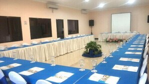 Une salle de conférence avec une longue table préparée pour une réunion, équipée de chaises, de verres d’eau et de porte-noms.