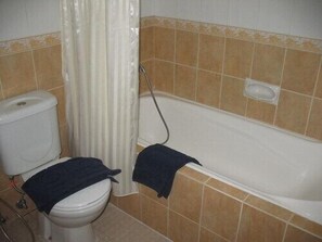 A bathroom with a toilet, a bathtub, and a shower curtain. - Atrium Resort & Hotel (Sukaradja)