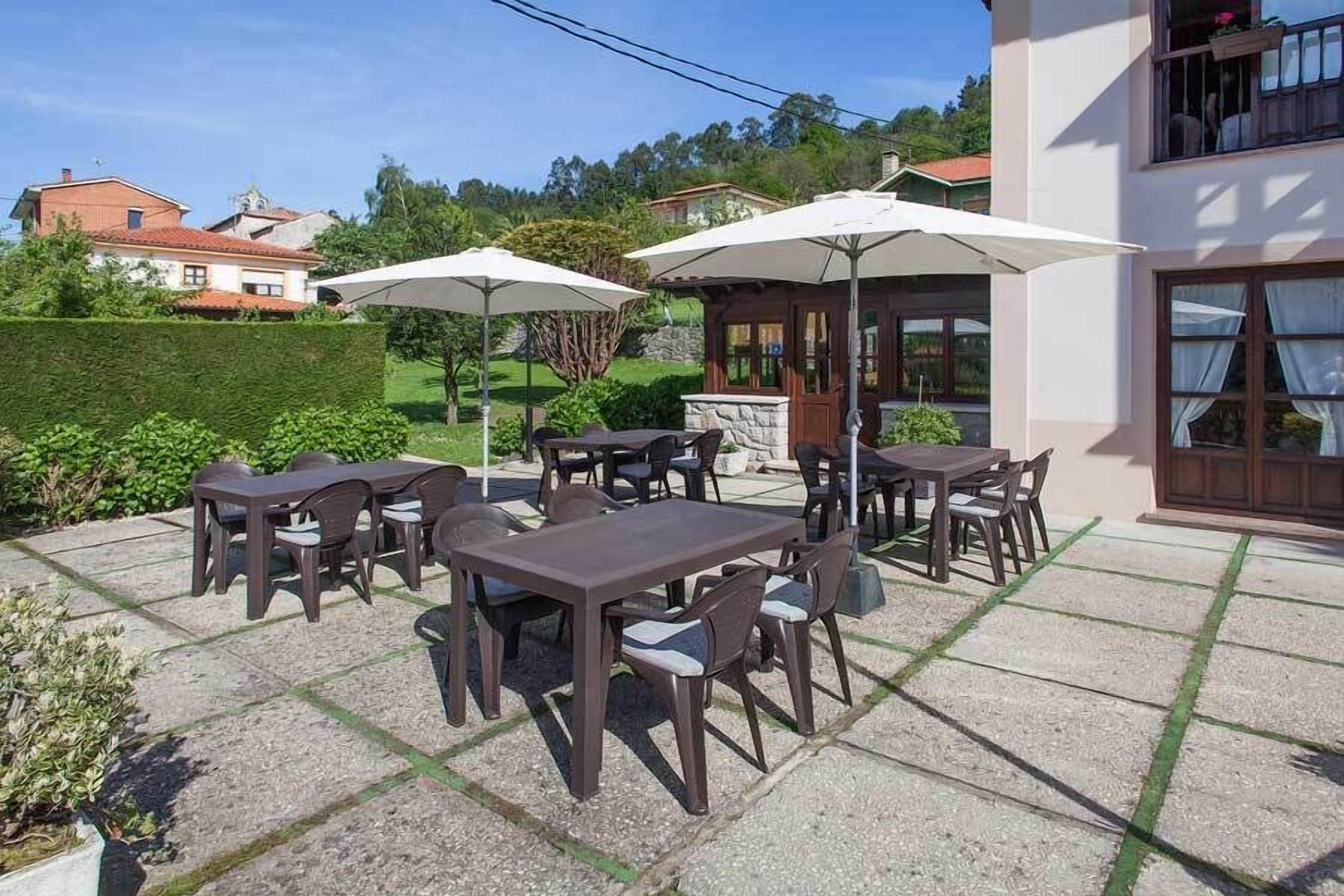 Une terrasse extérieure avec des tables et des chaises, des parasols, et un bâtiment en arrière-plan.