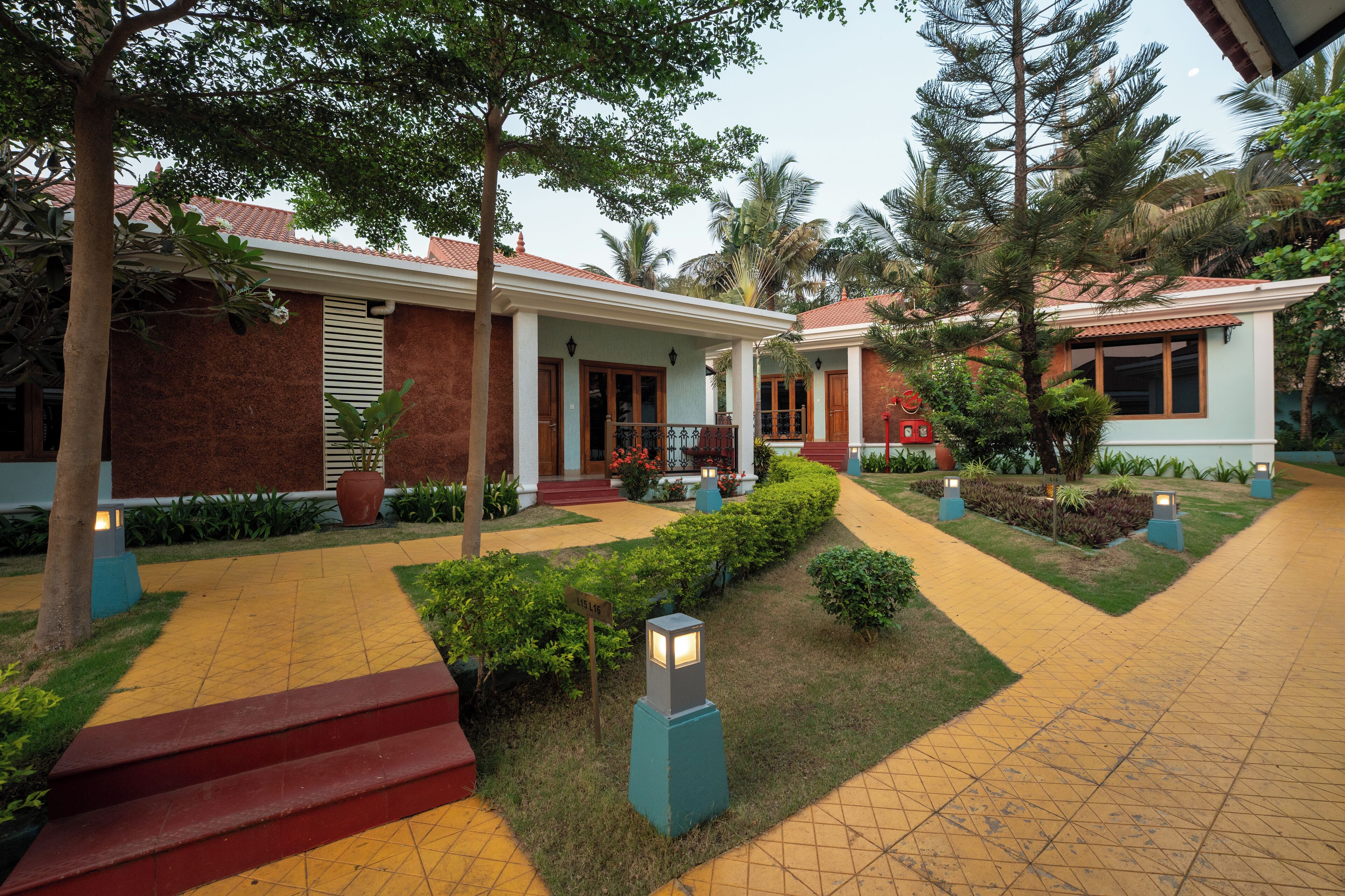 A well-maintained courtyard with a tiled walkway, steps leading to a covered entrance, and a variety of plants and shrubs.