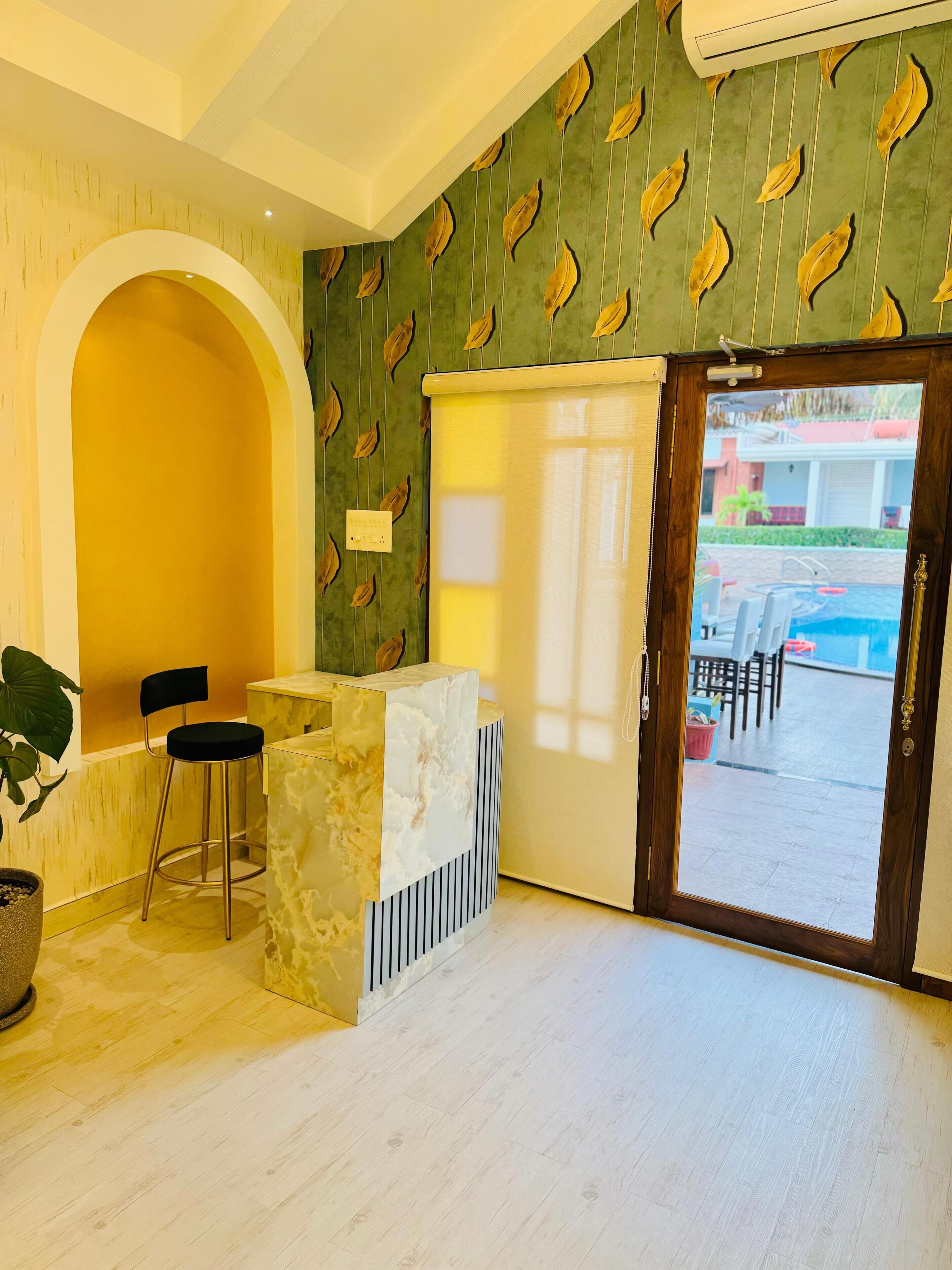 A reception area with a marble counter, two black chairs, a large potted plant, and a patterned wall.