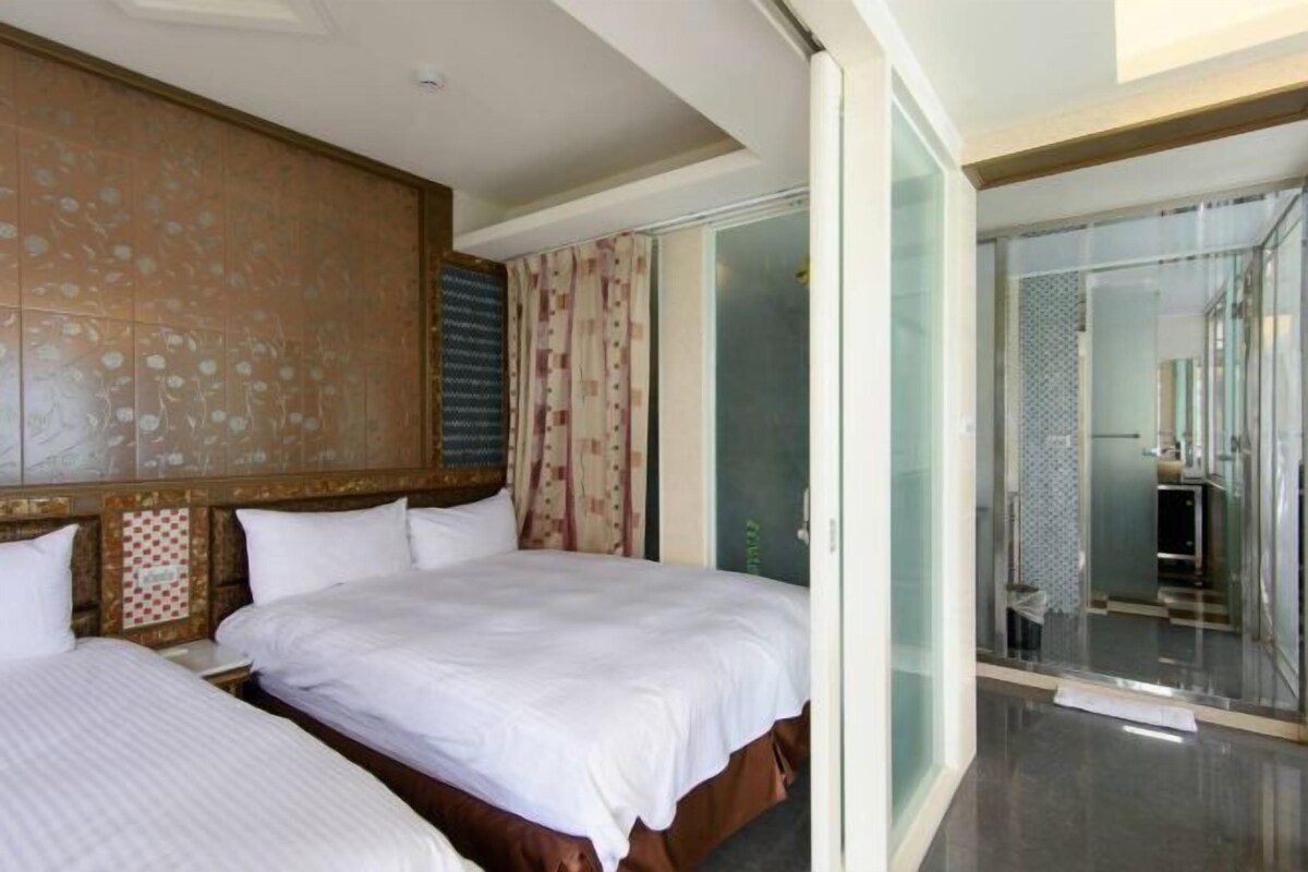 Ein Hotelzimmer mit zwei Betten, einer Schiebetür zum Badezimmer und einem gemusterten Kopfteil.