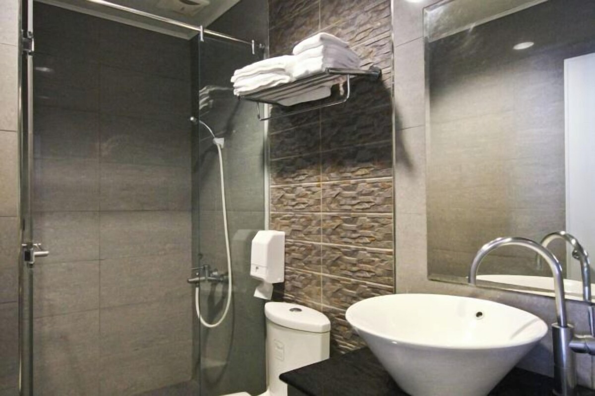 Ein modernes Badezimmer mit einer in Glas abgeschirmten Dusche, einem weißen Waschbecken und einem Handtuchhalter.