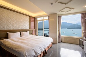 Une chambre d’hôtel avec un grand lit, une vue sur la mer et un balcon doté d’une balustrade.