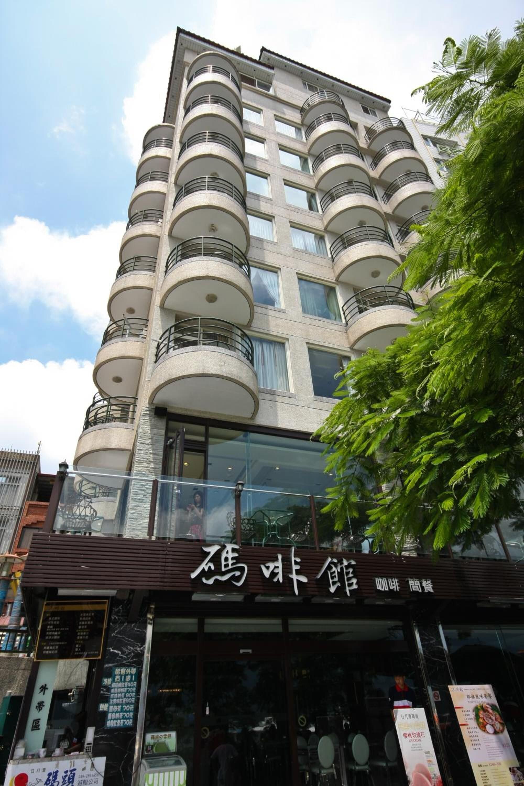 A multi-story building with balconies and a restaurant at the ground level.