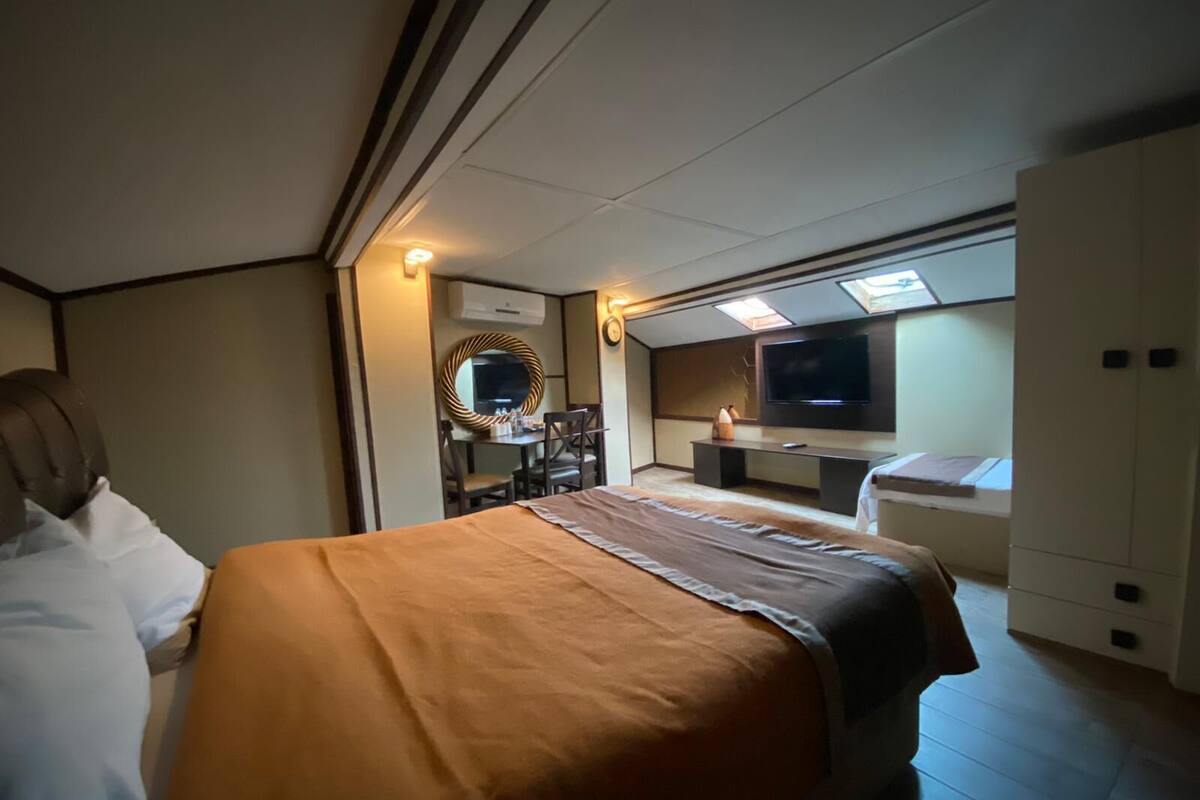 A hotel room with a bed, a desk, a TV, and a wardrobe.