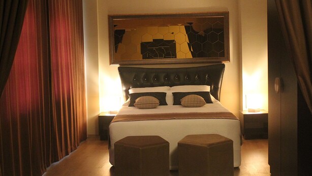 A hotel room with a large bed, two bedside tables, and a mirror above the bed. - Lena Central Flats (Bursa)
