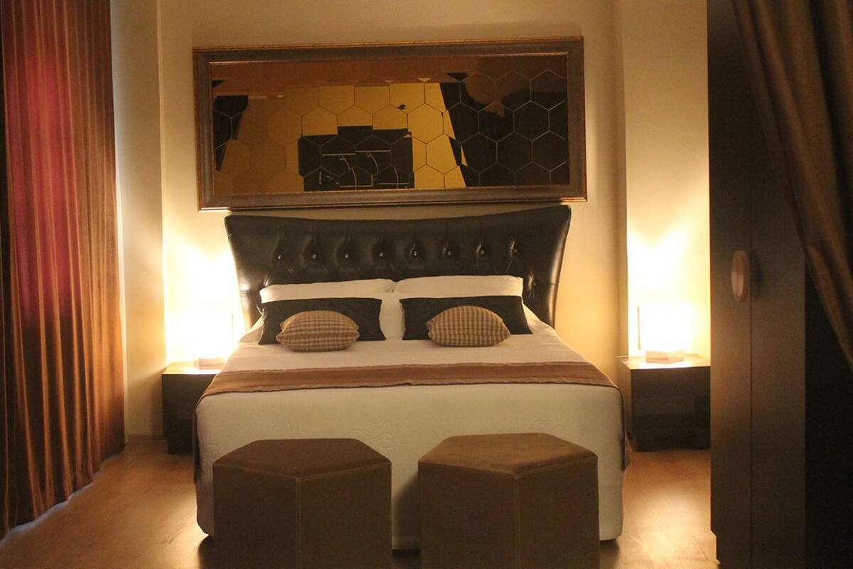 A hotel room with a large bed, two bedside tables, and a mirror above the bed.