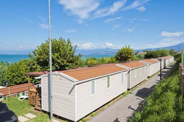 Una hilera de casas móviles con vista al mar y montañas al fondo.