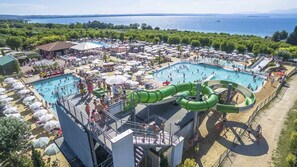 Un resort con varias piscinas, un tobogán de agua y vistas al mar.