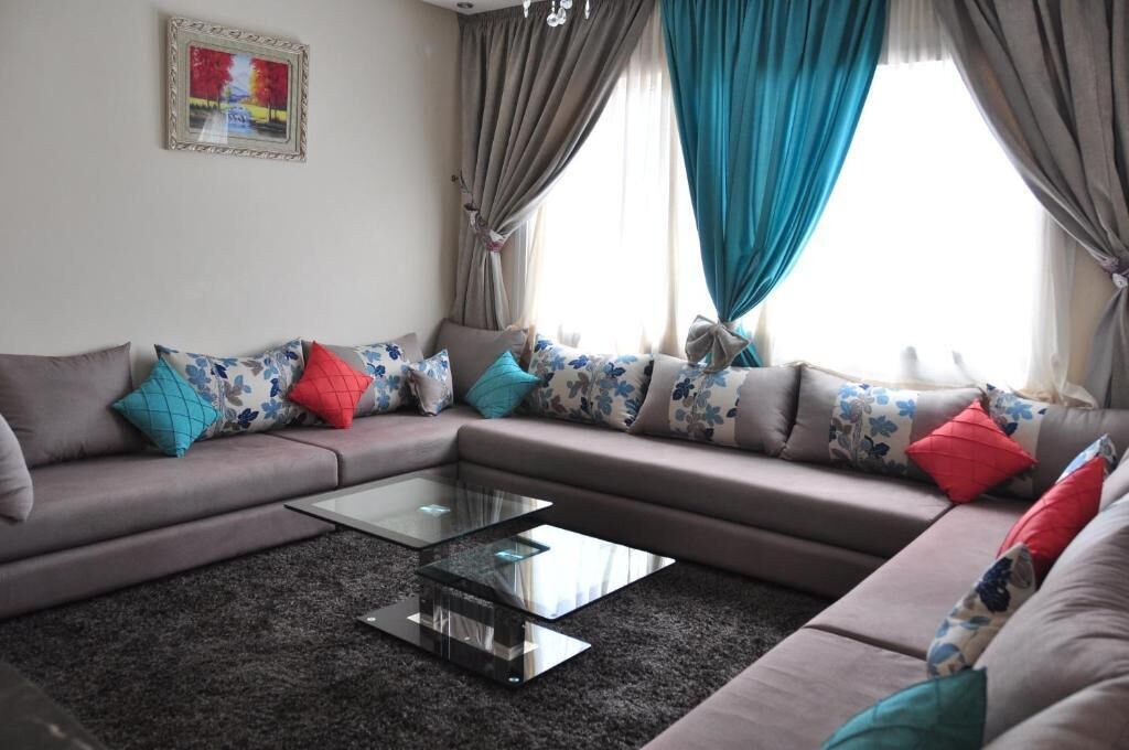 A living room with a sectional sofa, a glass coffee table, and colorful cushions.