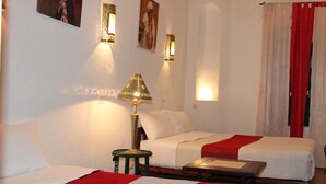 A hotel room with two beds, a small table, a chair, and a lamp. - Riad Dar El Qdima (Essaouira)
