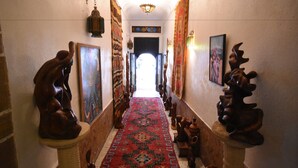 A hallway with a patterned carpet, wooden sculptures, and framed artwork on the walls. - Riad Dar El Qdima (Essaouira)