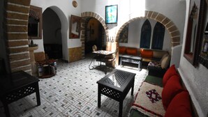 A traditional interior with arched doorways, a fireplace, and a seating area with cushions. - Riad Dar El Qdima (Essaouira)