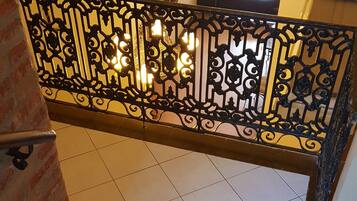 Una escalera con barandilla de metal decorativa y un candelabro.