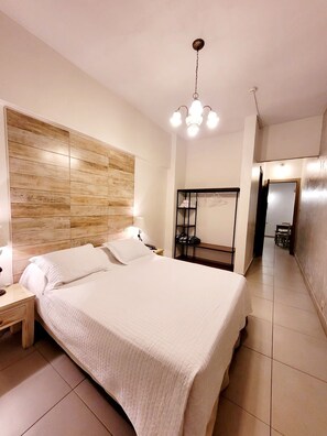 A bedroom with a large bed, bedside tables, a wooden headboard, a mirror, and a hanging light fixture. - Asunción Palace Hotel (Asunción)