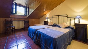 Een slaapkamer met twee bedden, houten vloeren, een schuine plafond en dakraam.