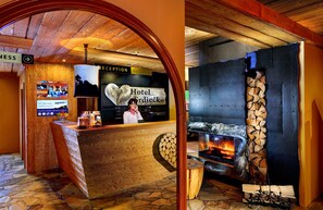 A reception area with a wooden reception desk, a sign for Hotel Srdiecko, and a stone wall with a fireplace.