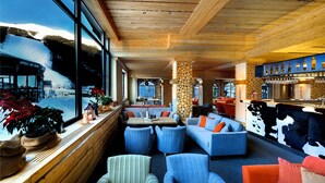 A cozy interior with a bar, seating area, and a view of a snowy landscape. - Hotel Srdiečko (Horna Lehota)