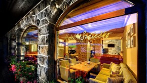 A hotel interior with a stone facade, indoor seating area with cushioned sofas and tables, and a visible bar area. - Hotel Srdiečko (Horna Lehota)
