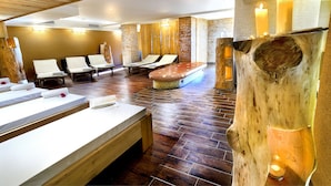 A spa room with wooden floors, multiple sun loungers, a large bench, and candles. - Hotel Srdiečko (Horna Lehota)