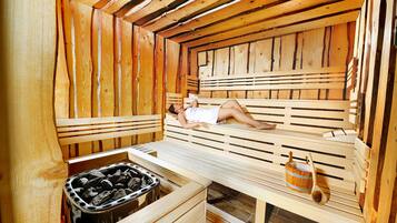 A wooden sauna with benches and a bucket of stones.