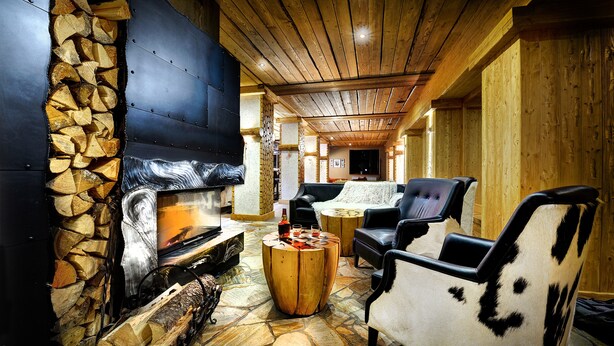 A cozy interior with a stone fireplace, wooden ceiling, and rustic furniture. - Hotel Srdiečko (Horna Lehota)