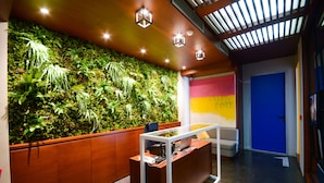 A reception area with a green wall, wooden desk, and a blue door. - Boutique Rooms (Belgrade)