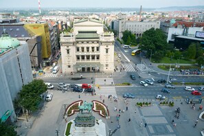 A large public square with a central statue, surrounded by buildings and a busy street.