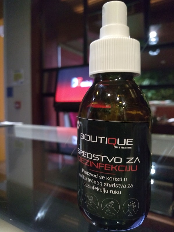 A bottle of disinfectant on a glass table with a blurred background.