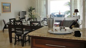 A dining area with a granite countertop, a large window with curtains, a television, and a dining table with chairs. - Beach Palace Cabarete (Cabarete)