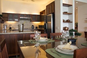 A modern kitchen with wooden cabinets, a stainless steel refrigerator, and a dining area set for a meal. - Beach Palace Cabarete (Cabarete)
