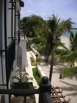 A balcony with a view of a beach and palm trees.