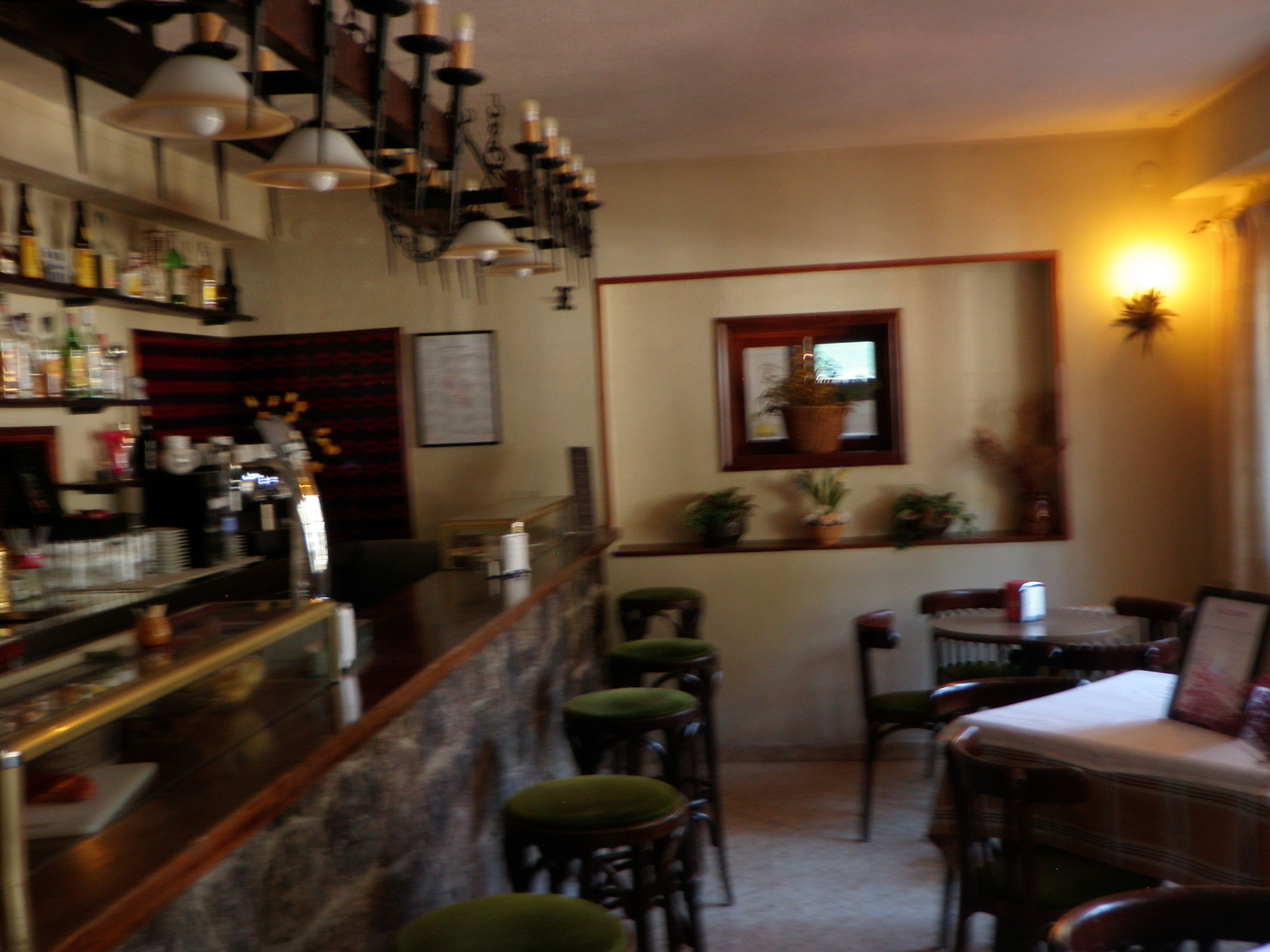 Una zona de bar con taburetes, una barra con botellas y un comedor con sillas y una mesa.