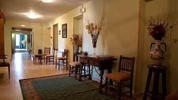 A hallway with a dining area featuring wooden chairs, a table, and a vase with dried plants.