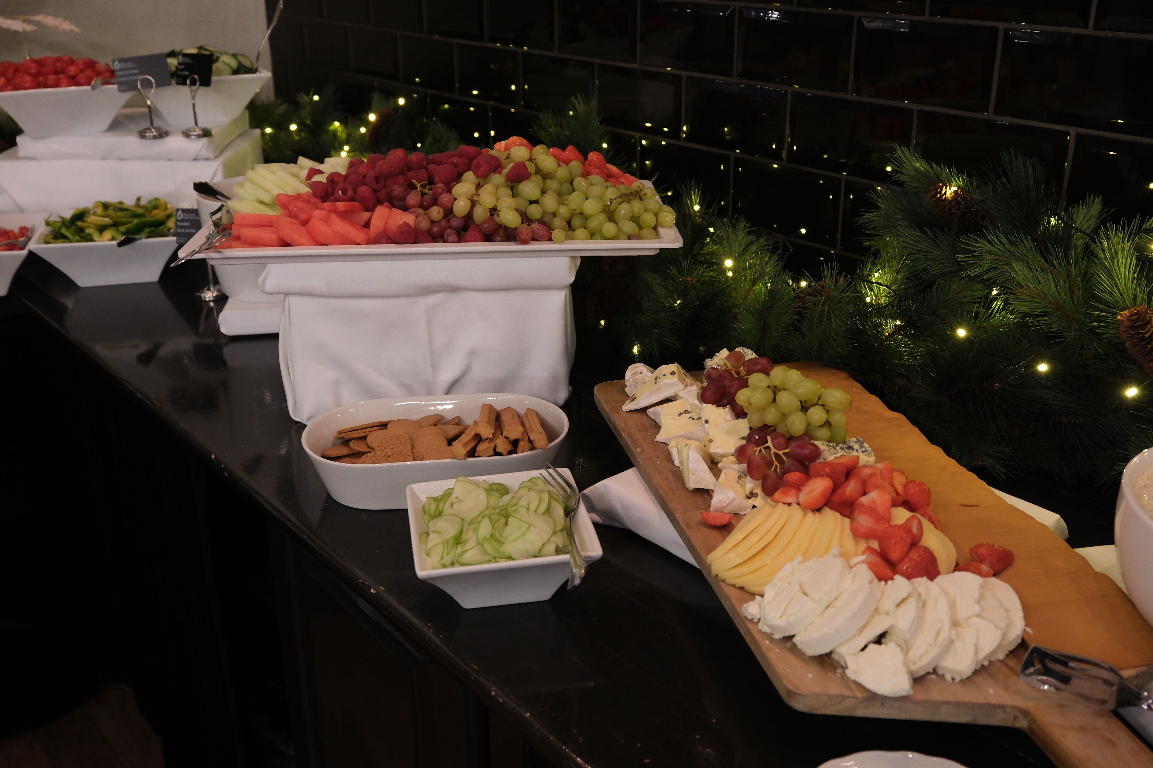 A buffet with various fruits, cheeses, and crackers.