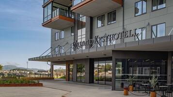 Un hotel moderno con una entrada destacada, zona de estar al aire libre y vistas del paisaje circundante.